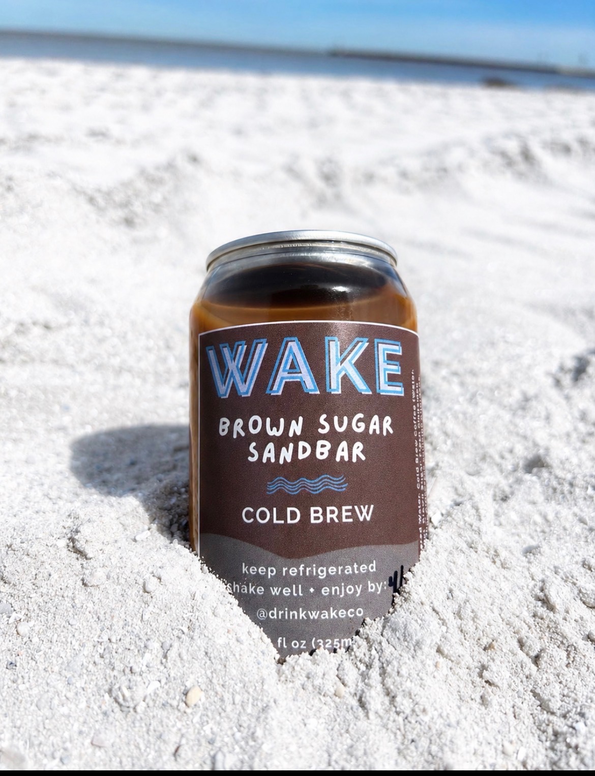 Brown Sugar Sandbar WAKE cold brew can standing in white beach sand